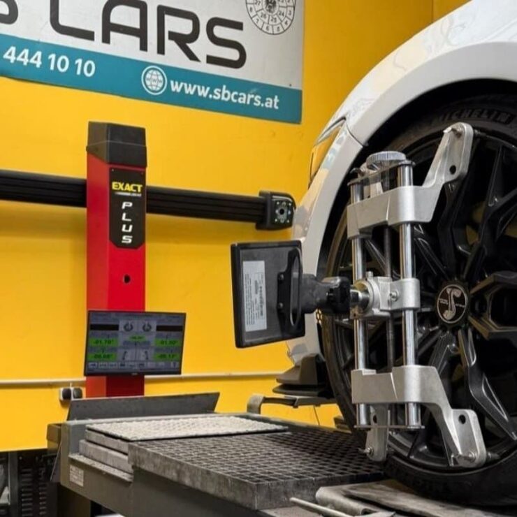 Präzise Spureinstellung mit moderner Achsvermessungstechnik in einer KFZ-Werkstatt in Wien. Das Fahrzeug steht auf der Hebebühne, während Sensoren an den Rädern montiert sind.
