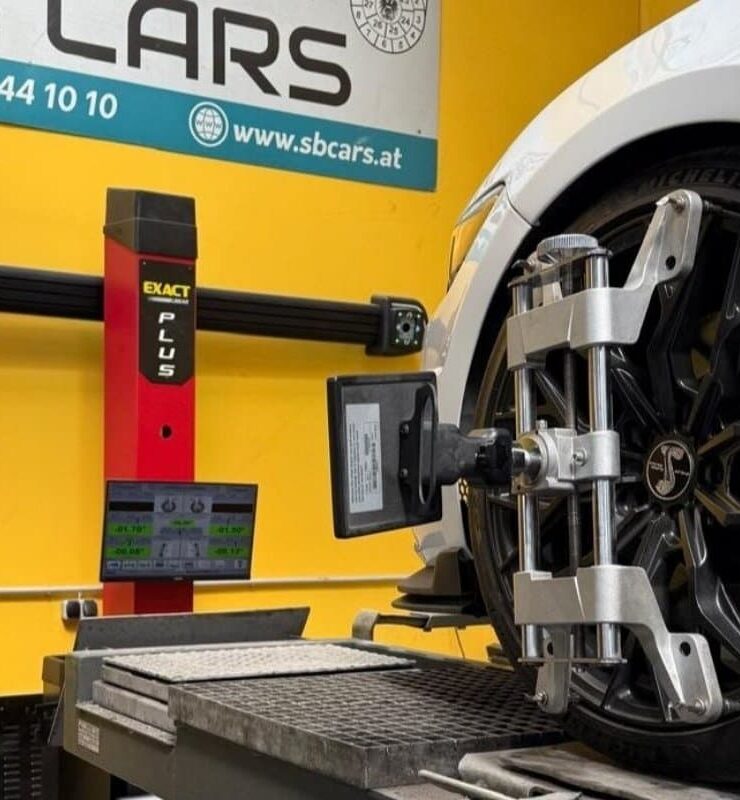 Präzise Spureinstellung mit moderner Achsvermessungstechnik in einer KFZ-Werkstatt in Wien. Das Fahrzeug steht auf der Hebebühne, während Sensoren an den Rädern montiert sind.