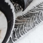 Ein Mechaniker wechselt Winterreifen an einem Auto in Wien. Nahaufnahme der Reifenmontage im Winter, sicherer Reifenservice bei kalten Temperaturen.