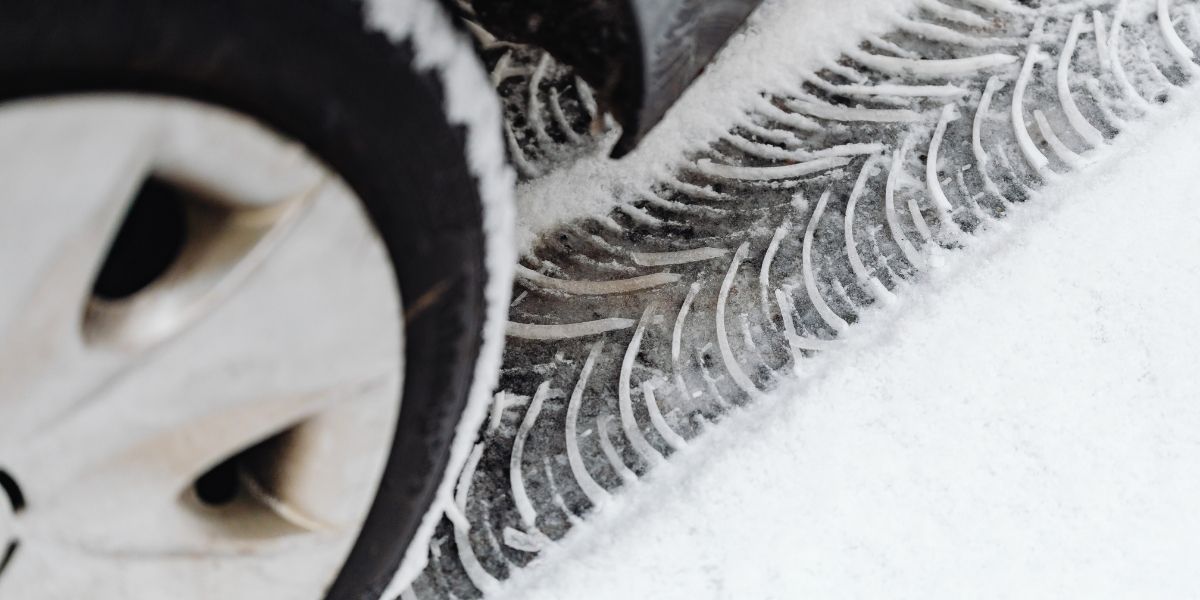 Ein Mechaniker wechselt Winterreifen an einem Auto in Wien. Nahaufnahme der Reifenmontage im Winter, sicherer Reifenservice bei kalten Temperaturen.